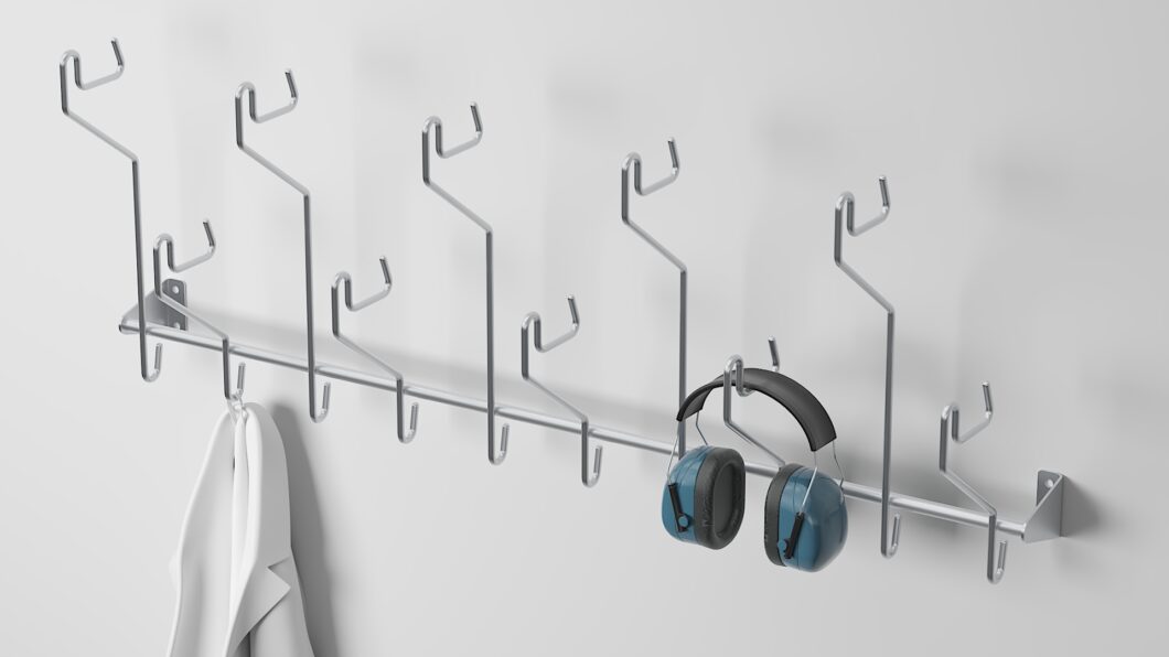 Stainless steel wall-mounted hook rack with 10 hooks holding hearing protectors and gear.